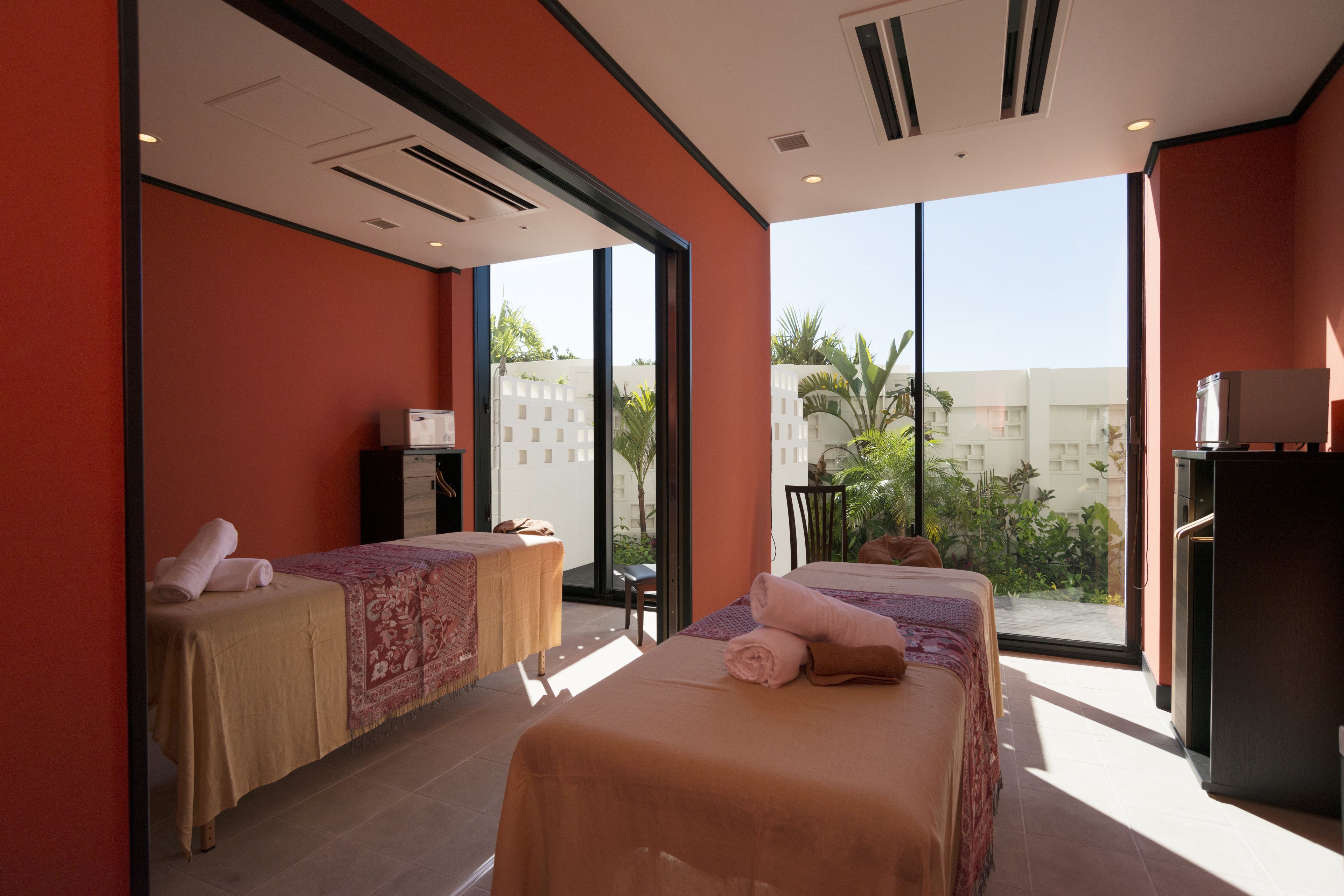 Quarto de hotel moderno com duas camas, uma mesa de massagem e uma grande janela com vista para a cidade.