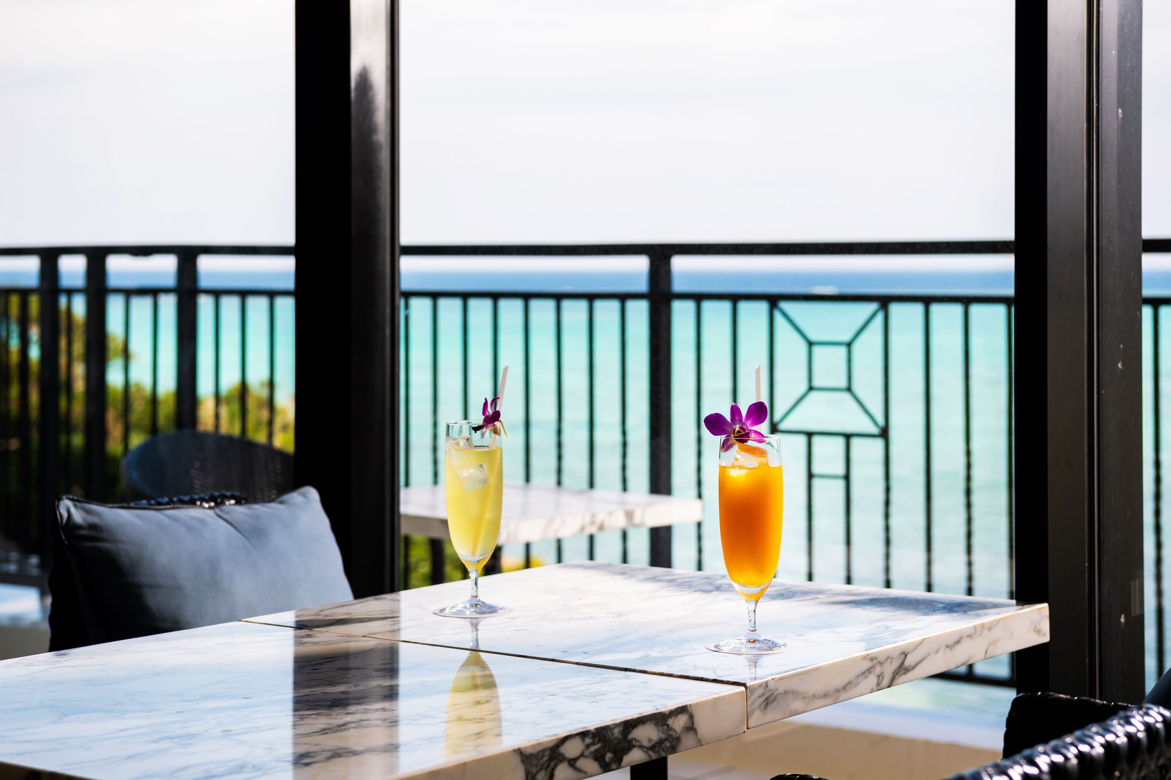 Uma mesa com duas bebidas e vista para o oceano.