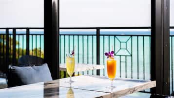 Uma mesa com duas bebidas e vista para o oceano.