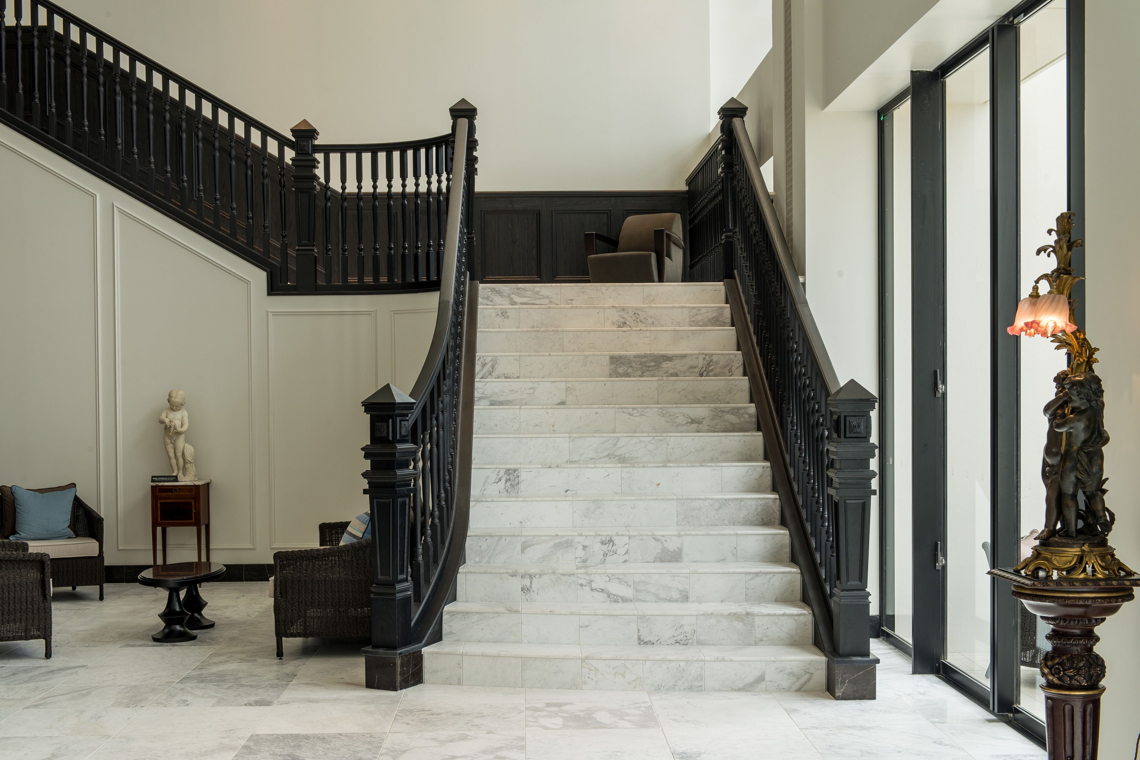 Un magnifique escalier en marbre, avec des marches en marbre et des rampes noires, menant à l’étage supérieur.