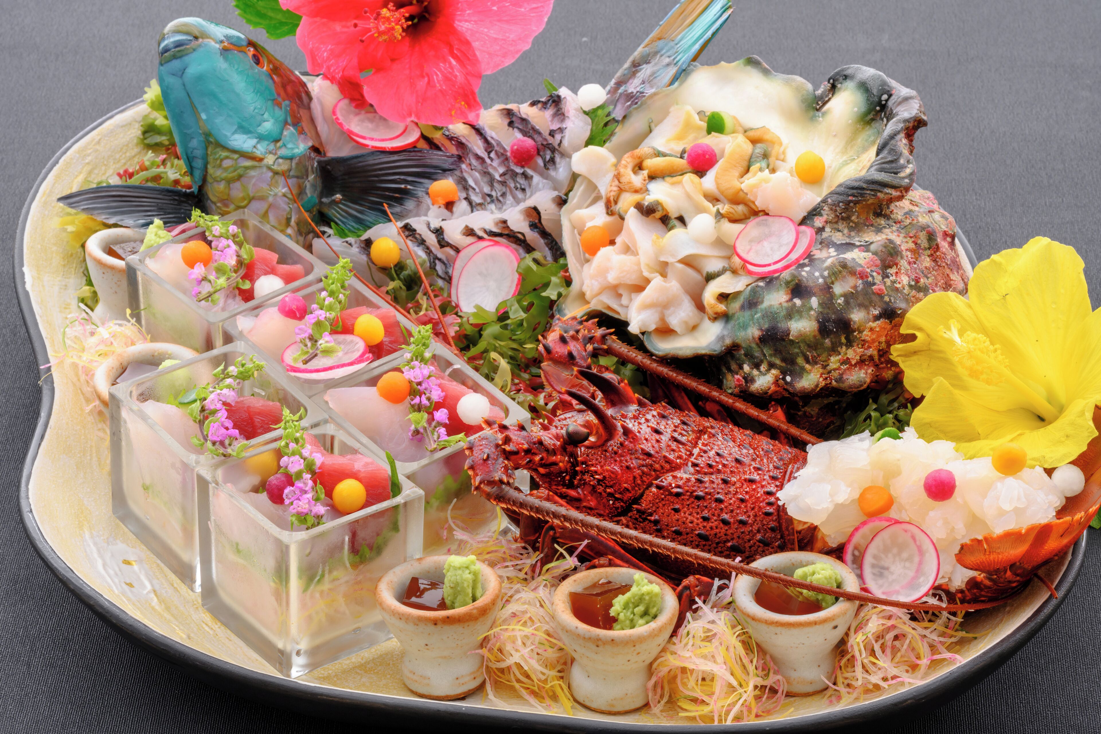 A seafood platter with various items including a lobster, shrimp, and other seafood, along with decorative elements like flowers and a bird figurine.