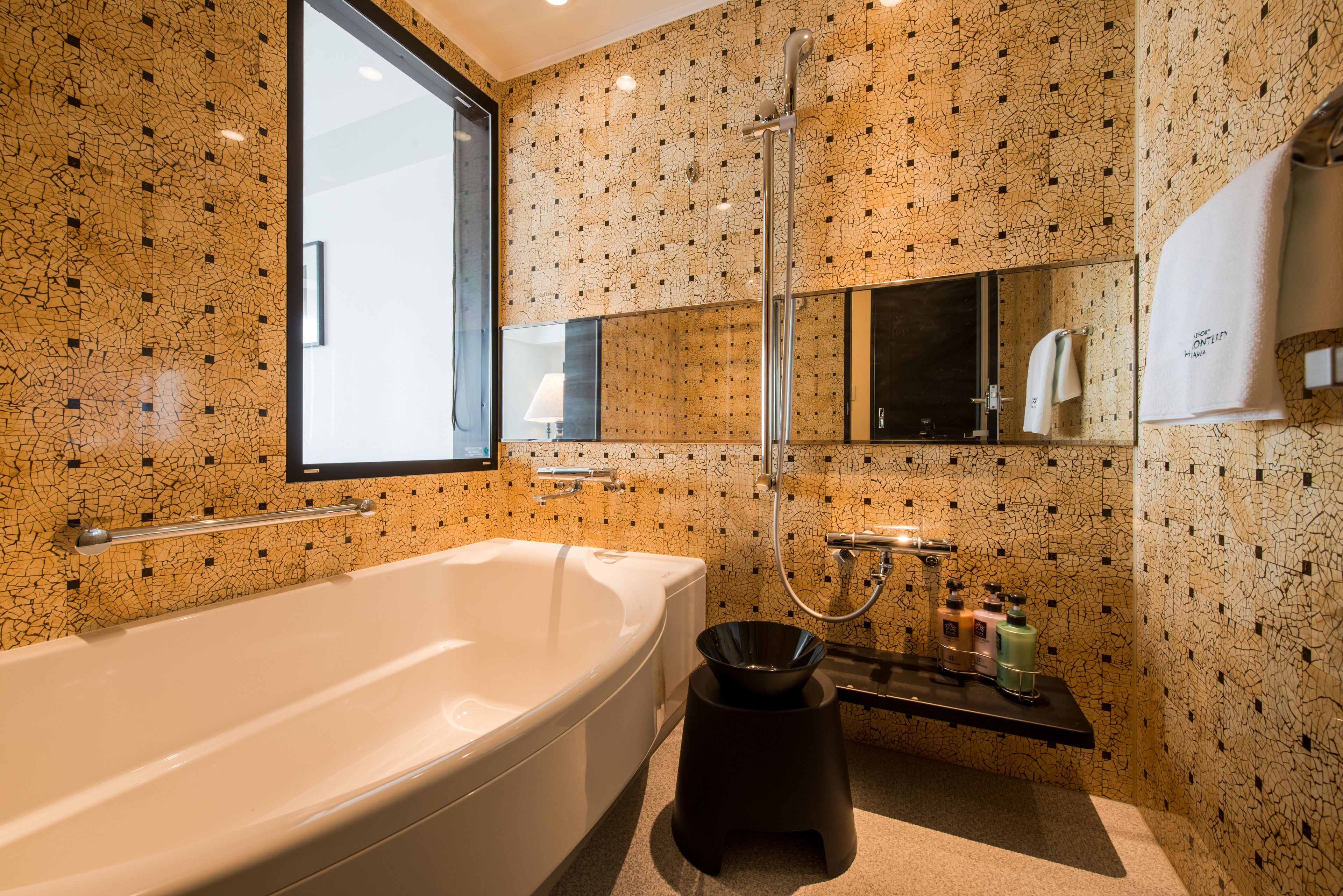 A modern bathroom with a large bathtub, a shower, and a sink with toiletries.
