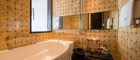 Een moderne badkamer met een ruime badkuip, een douche en een wastafel met toiletartikelen.