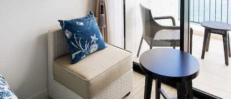 Una habitación con un sofá de mimbre, una mesa redonda y vistas al balcón exterior.