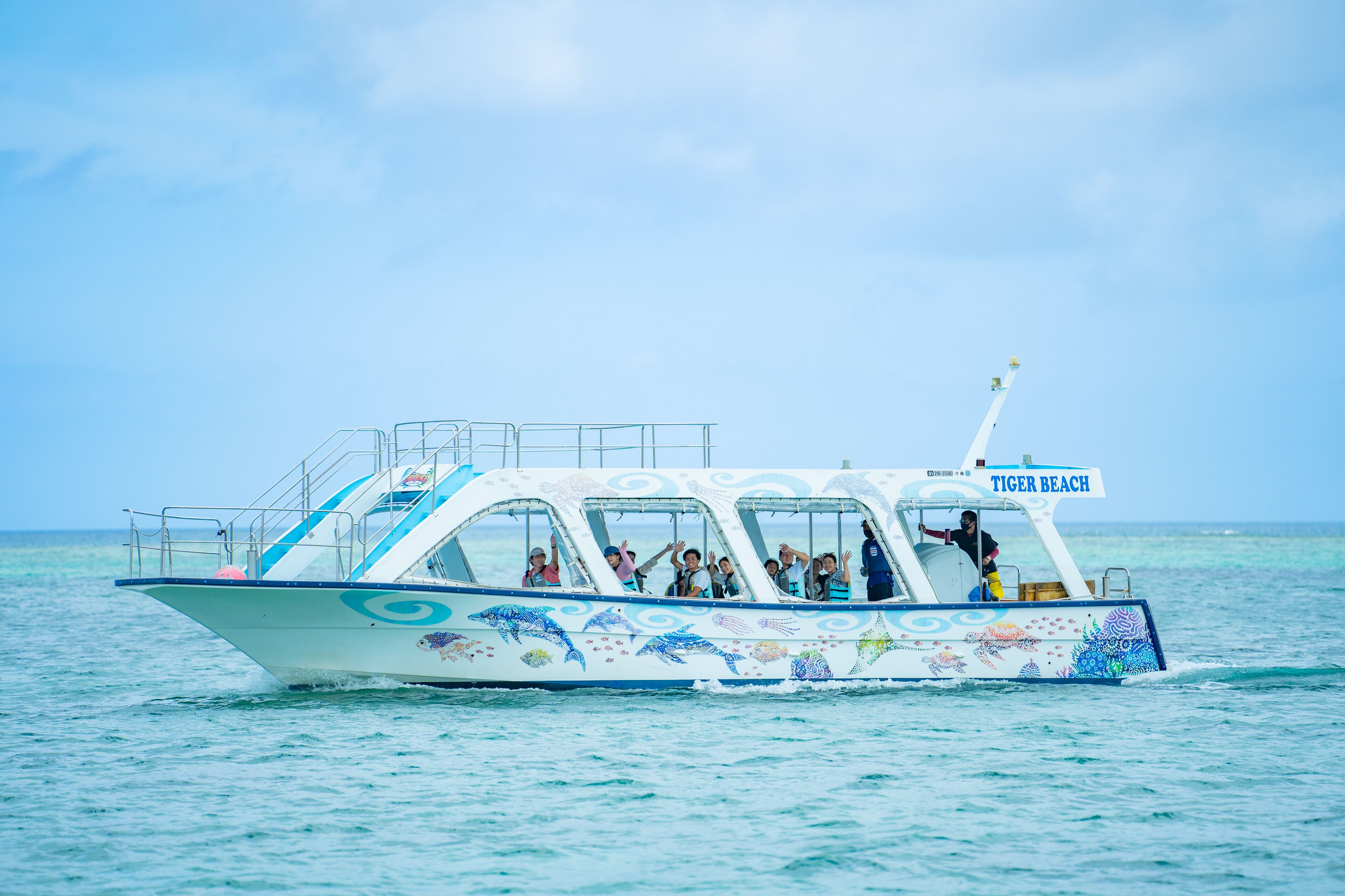 A boat with the name "Tiger Beach" on the front, carrying passengers.