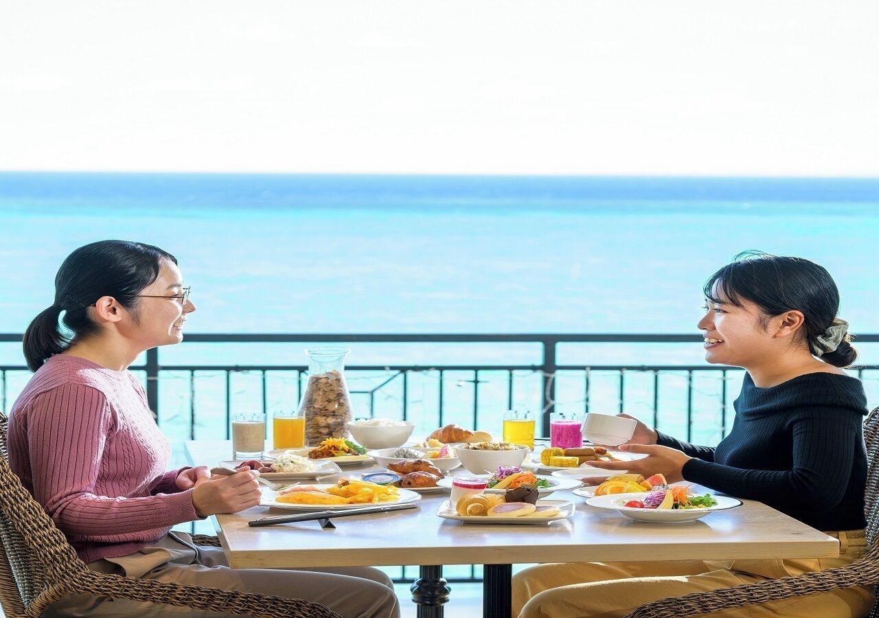 Two people dining at a table with a view of the ocean.