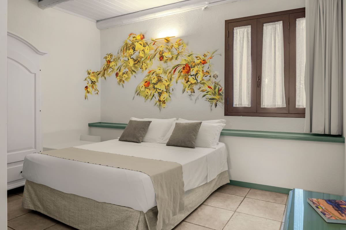 Un dormitorio con una cama, una ventana con cortinas y una pared con un mural floral.