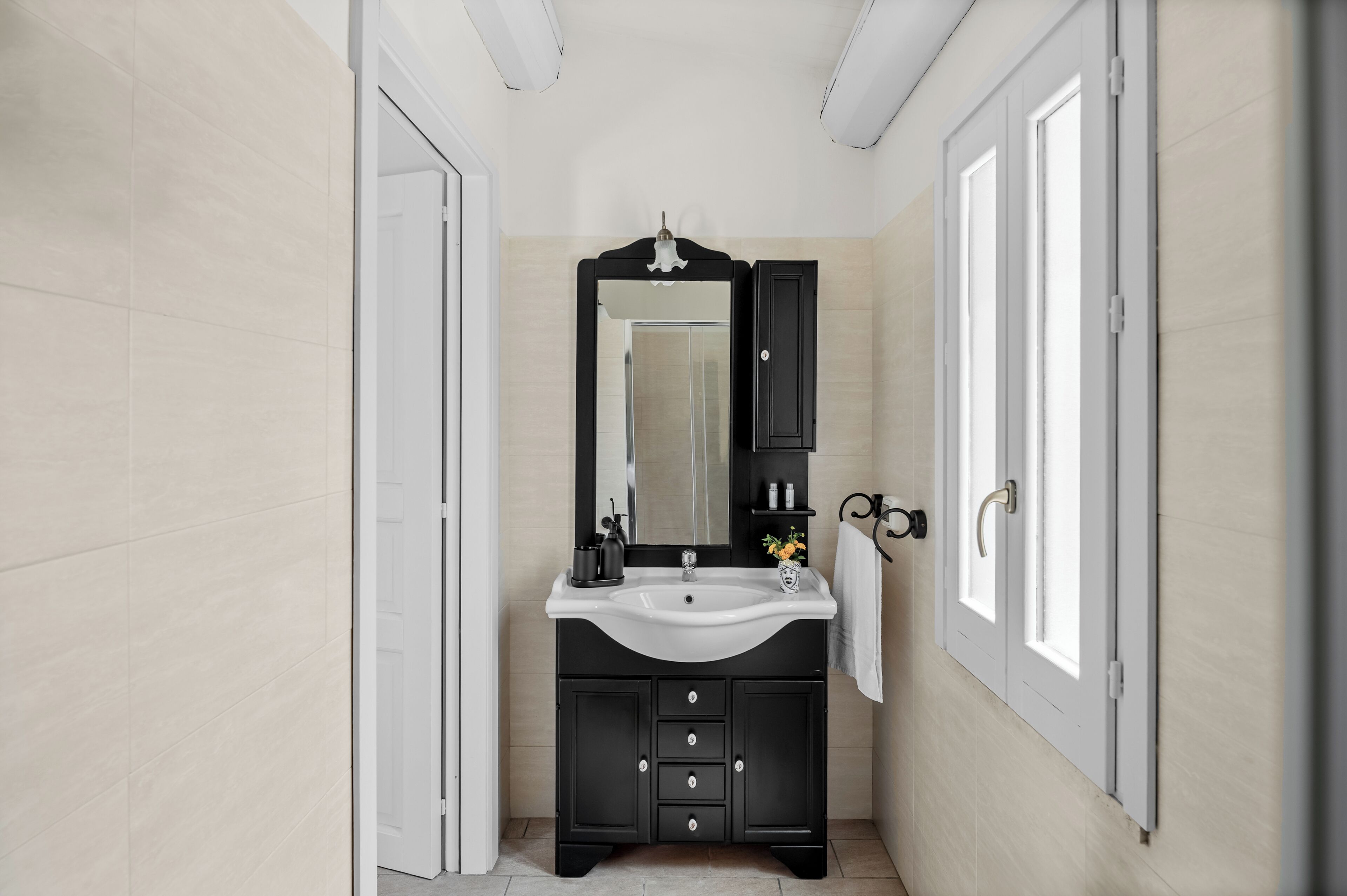 A modern bathroom with a black vanity, white sink, and a large mirror.