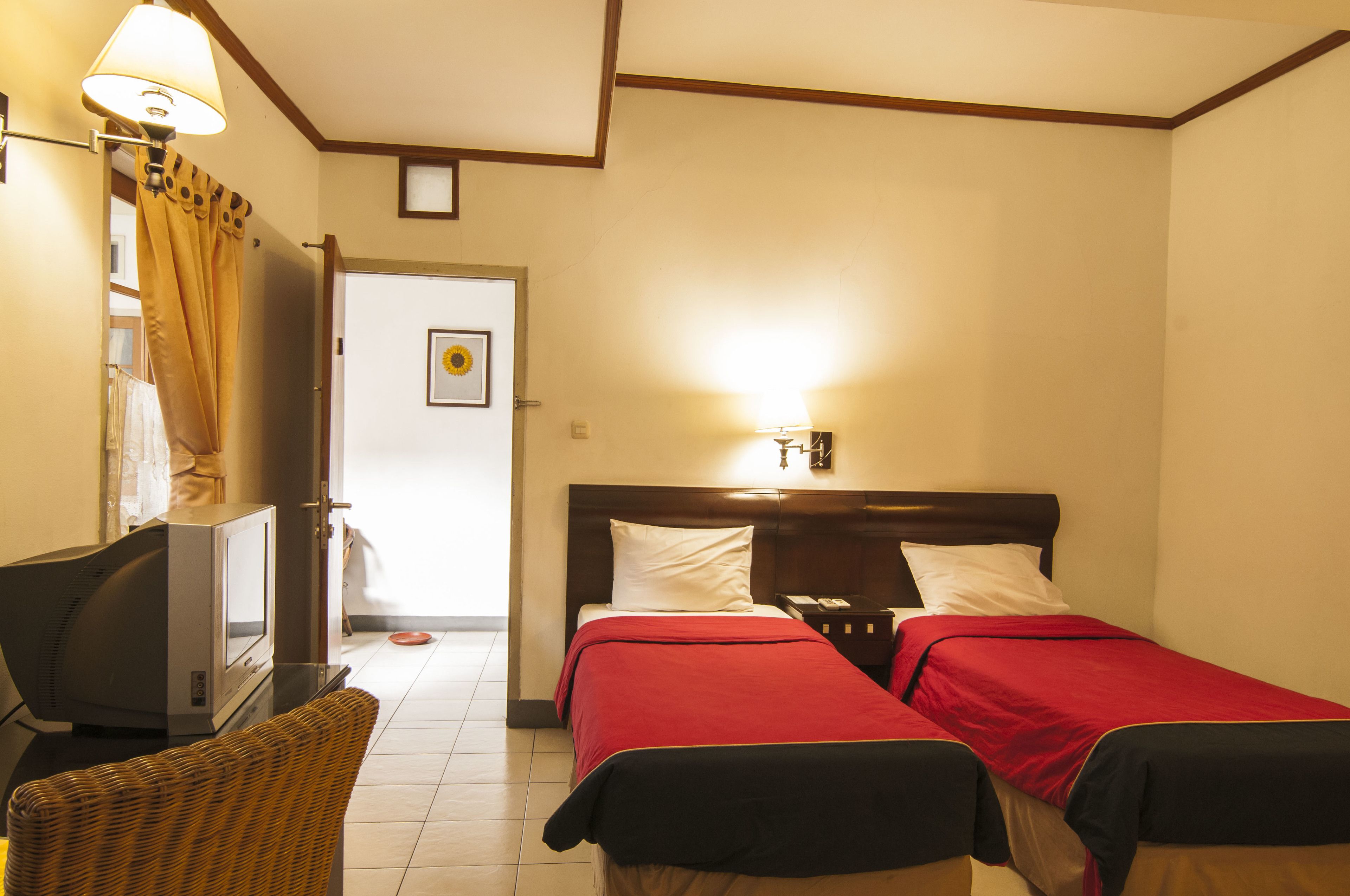 A hotel room with two beds, a television, a chair, and a door leading to a bathroom.