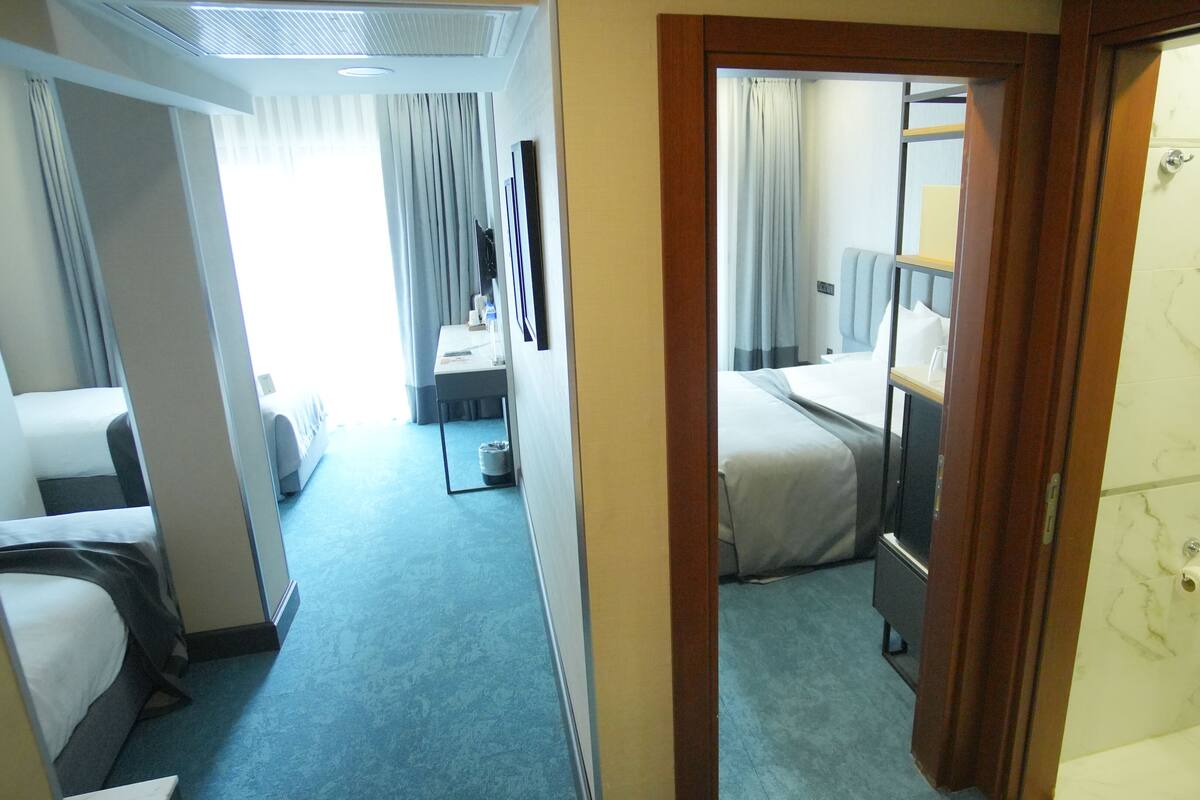 A hotel room with a bed, a desk, and a bathroom.
