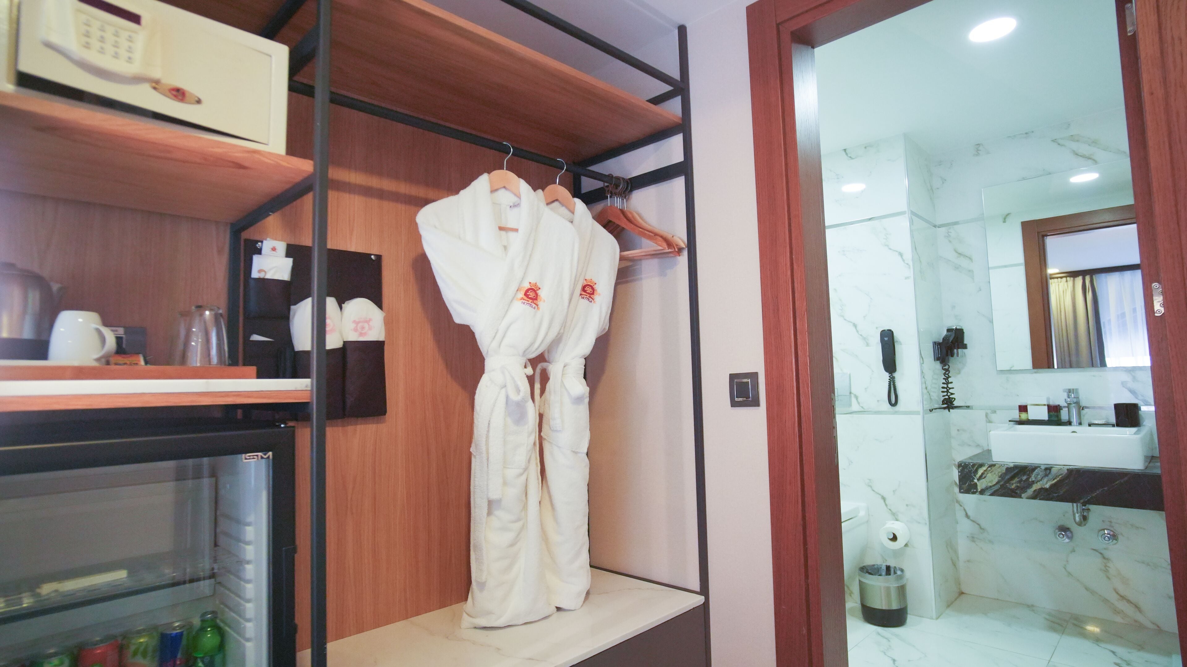 A hotel bathroom with a marble sink, a shower, and a robe hanging on a rack.