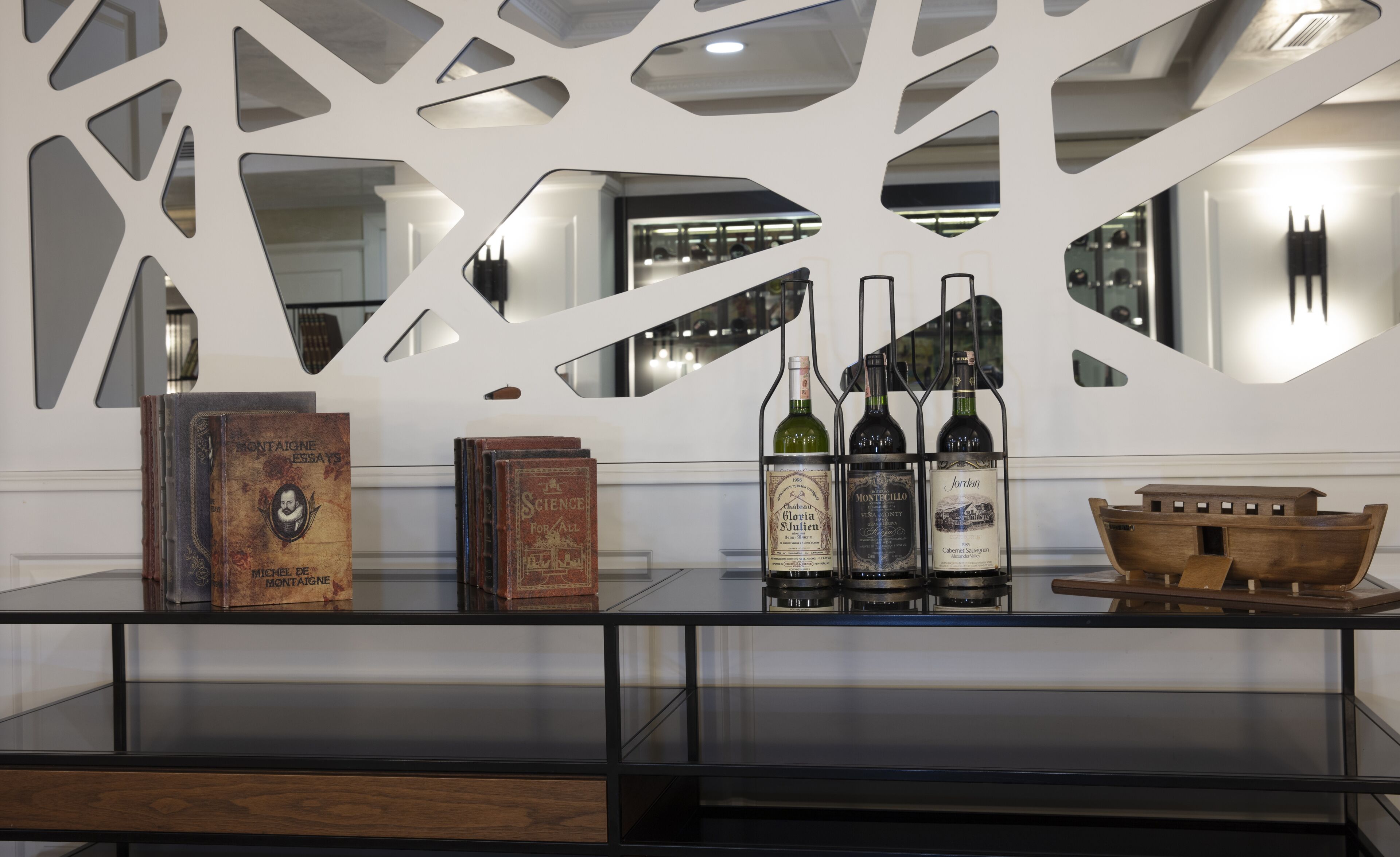 Um interior moderno com uma mesa de vidro exibindo livros e garrafas de vinho.