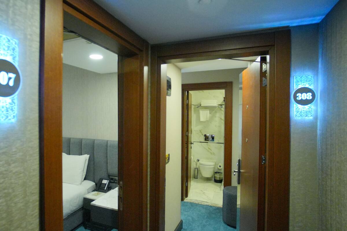 A hotel room with a bed, bedside table, and a bathroom visible through an open door.