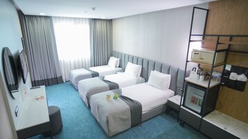 Una habitación de hotel con dos camas, un escritorio, un espejo, un minibar y una ventana con cortinas.