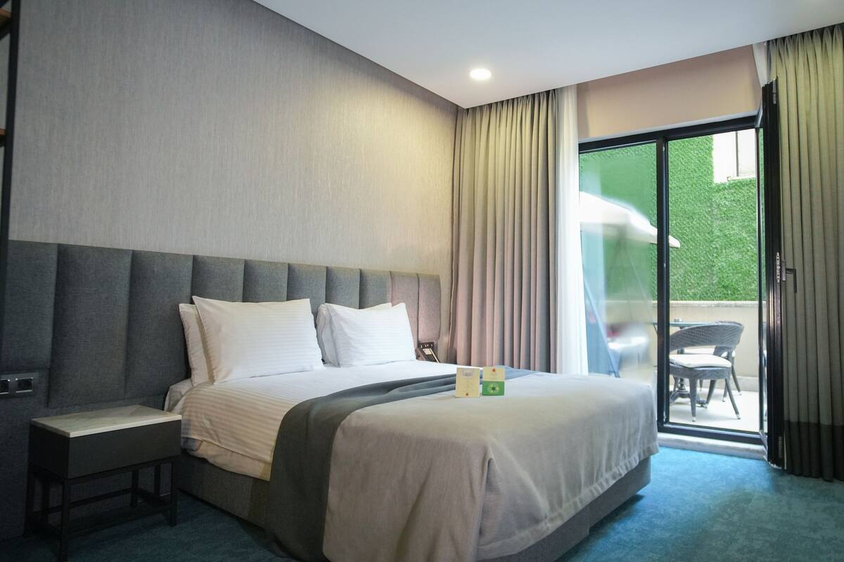 A hotel room with a bed, a desk, and a view of the outdoors.