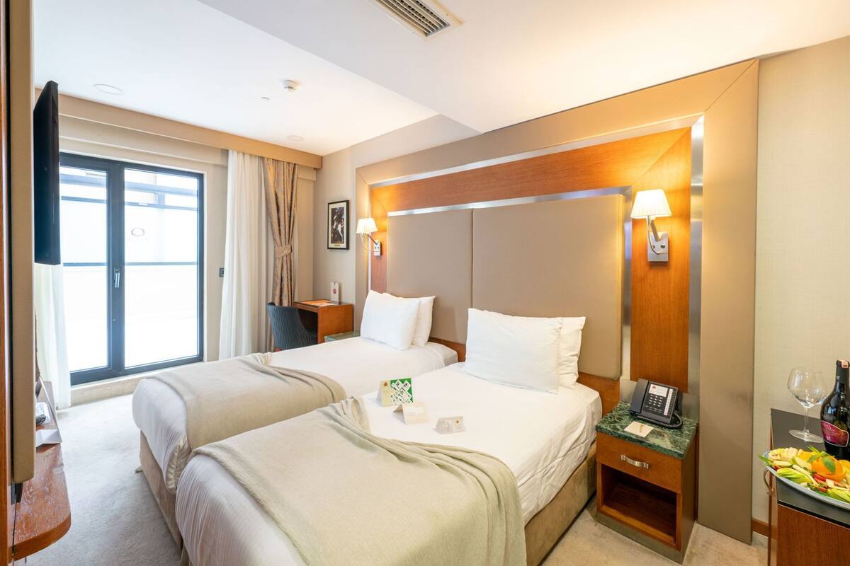A hotel room with two beds, a desk, a phone, and a minibar.