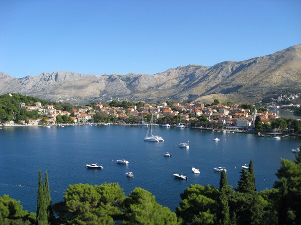A coastal town with boats in a harbor, surrounded by mountains. - Hotel Supetar Cavtat (Konavle)