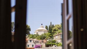 A view through a window of a building with a dome, surrounded by stone houses and trees. - Hotel Supetar Cavtat (Konavle)