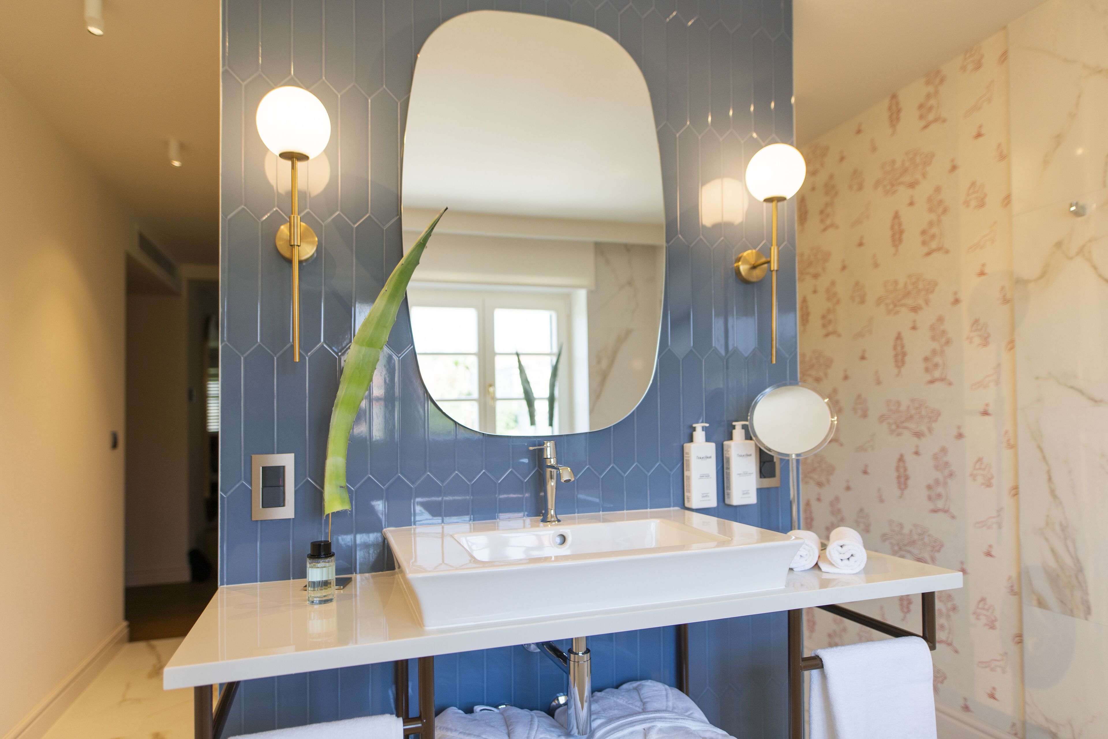 A bathroom with a white sink, a large mirror, and two wall-mounted lights.