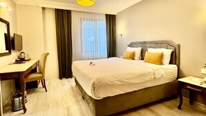 A hotel room with a bed, a desk, a chair, a small table, and a window with curtains. - Asia City Hotel Istanbul (Istanbul)