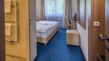 Een hotelkamer met een bed, bureau, stoel, spiegel en douche.
