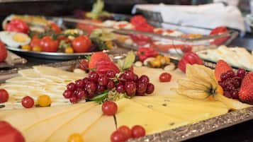 Een buffet met verschillende kazen, fruit en groenten.