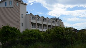 Un edificio residencial de varios pisos con un diseño arquitectónico moderno, que cuenta con balcones y unidades de aire acondicionado.