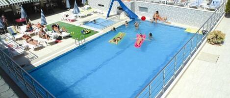 Zona de piscina con sillas de descanso, sombrillas y un tobogán.