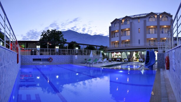 Una piscina con sillones de descanso y un restaurante al fondo.