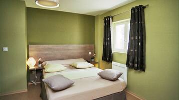 Un dormitorio con cama, mesitas de noche, lámpara y ventana con cortinas.