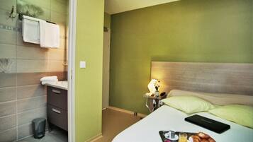 A hotel room with a bed, bedside table, lamp, and a tray with food.