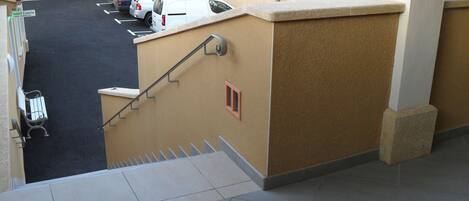 Un estacionamiento con coches, una escalera y la fachada de un edificio.