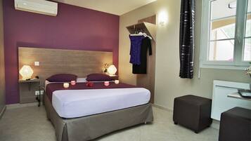 A bedroom with a bed, bedside lamps, a dresser, and a window with curtains.