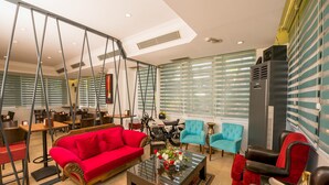 A modern interior with a red sofa, blue armchairs, and a glass coffee table. - Mera Park Hotel (Antalya)
