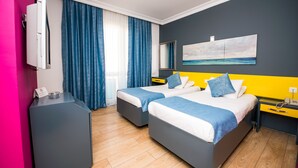 A hotel room with two beds, a desk, a mirror, and a painting of a beach. - Mera Park Hotel (Antalya)