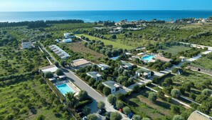 Vista aérea de un complejo turístico con varias construcciones, piscina y vistas al mar.