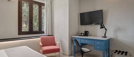 Une chambre d’hôtel avec un lit, un bureau et une chaise, une télévision et une fenêtre avec des rideaux.