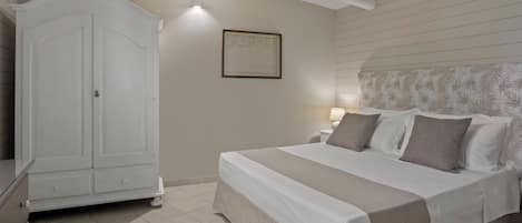 A bedroom with a bed, a wardrobe, a nightstand, and a wall-mounted light fixture.