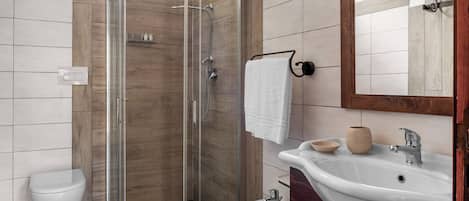 A modern bathroom with a glass-enclosed shower, a white sink, and a bidet.