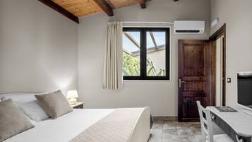 A bedroom with a bed, bedside table, lamp, window, and a desk with a chair.