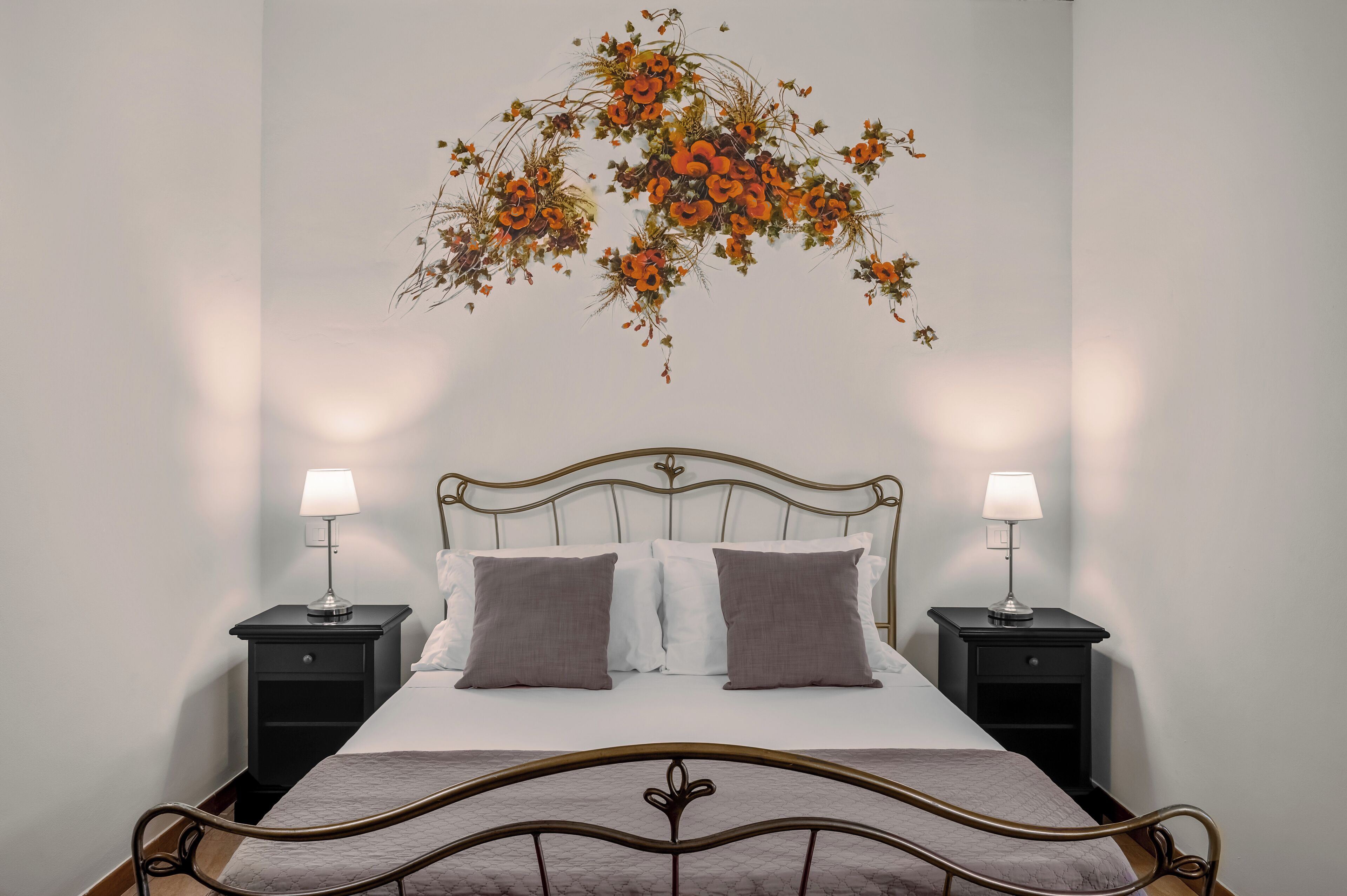 A neatly made bed with a headboard, two bedside tables with lamps, and a wall decoration above the bed.
