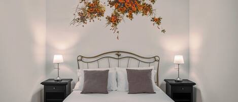 A neatly made bed with a headboard, two bedside tables with lamps, and a wall decoration above the bed.