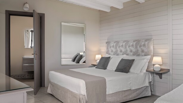 Ein Schlafzimmer mit einem Bett, Nachttischen, einem Spiegel und einem Kleiderschrank.