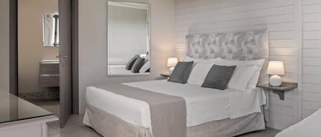 A bedroom with a bed, bedside tables, a mirror, and a wardrobe.