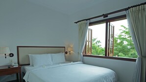 A hotel room with a bed, a bedside table with a lamp, a telephone, and a window with curtains. - Sokhalay Angkor Inn (Siem Reap)