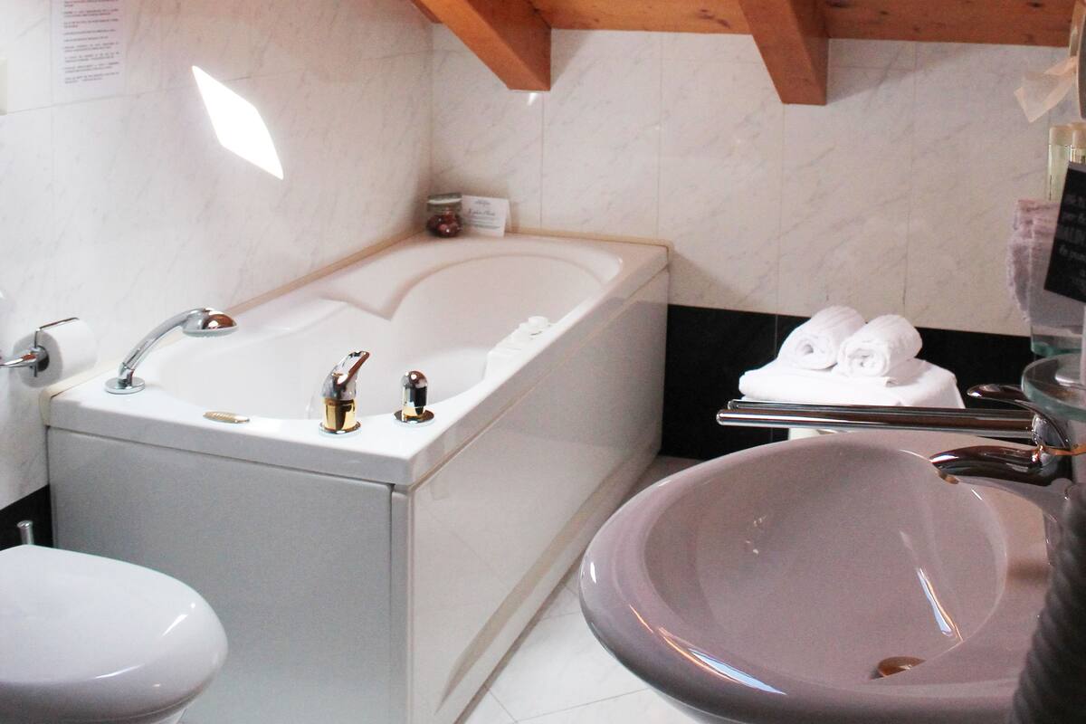 A bathroom with a skylight, a bathtub, a sink, and a toilet.