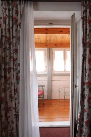 Una habitación con suelo de madera, una silla roja y una pequeña mesa.