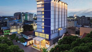 A modern hotel with a prominent blue and white facade, multiple floors, and a well-lit entrance area.