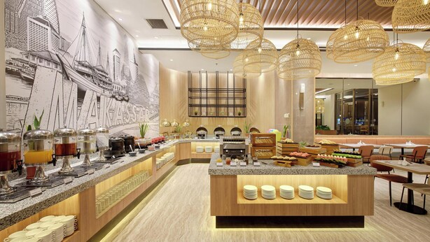 A modern breakfast bar with a cityscape mural, a variety of food and drink dispensers, and a central island with plates.
