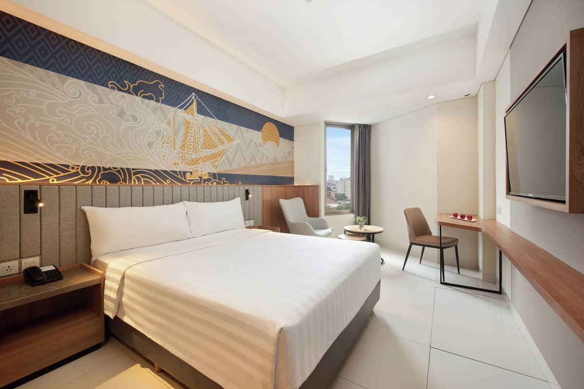 Een moderne hotelkamer met een groot bed, een bureau, twee stoelen, een televisie en uitzicht over de stad.
